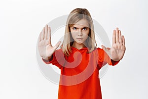 Serious little girl showing stop, prohibition taboo gesture, extending arms and blocking smth bad, rejecting, standing