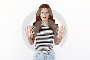 Serious-looking annoyed and disappointed young redhead woman in striped t-shirt wanna finish conversation, show raised