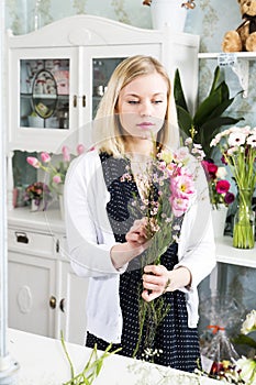 Serious looking female creating the composition with flowers