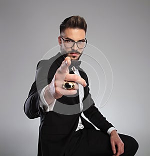 Serious looking groom pointing forward while wearing glasses