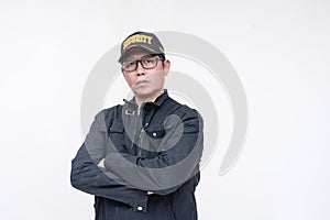 A serious looking male security guard in a black jacket and arms crossed. A male, asian and in his 40s. Isolated on a white