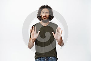 Serious looking man stretching out hand, showing stop rejection gesture, saying no, decline something, standing over photo