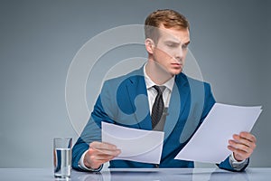 Serious-looking newscaster reading his papers