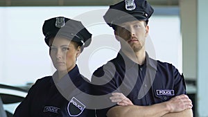 Serious-looking police officers in hats posing on camera, district security