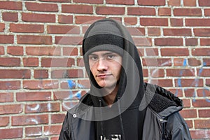 Serious looking teenage boy in front of a brick wall