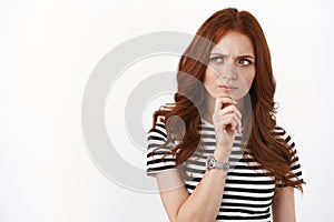 Serious-looking young redhead woman scheming something, look suspicious and hesitant, having doubts, express trong