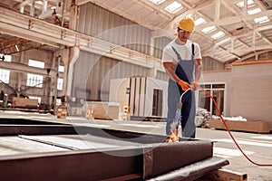 Serious male builder using gas burner at construction site