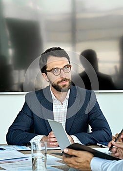 Serious male ceo discussing company strategy at boardroom table meeting.