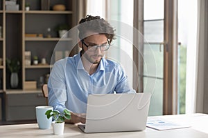 Serious male freelancer in glasses working at homeoffice