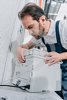 Serious male handyman repairing copy machine photo