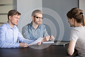 Serious male hr team listening female applicant at job interview
