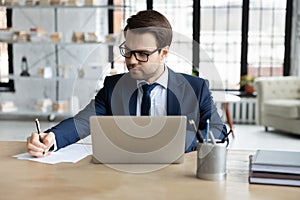 Serious male legal expert checking document at workplace