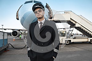 Serious male pilot in uniform waiting for flight in airport