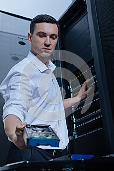 Serious male technician working with the network server