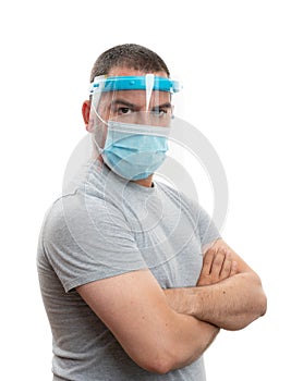 Serious man with arms crossed wearing protective screen and mask