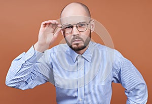 A serious man with a beard and round glasses bent down in the camera