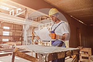 Serious man builder studying architectural plan at construction site