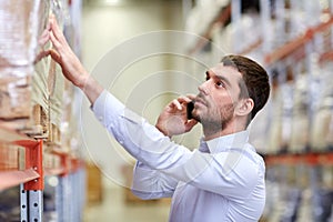 Serious man calling on smartphone at warehouse