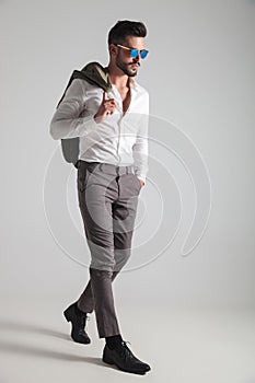 Serious man with coat on shoulder stepping forward