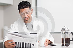 Serious man with coffee cup reading newspaper photo