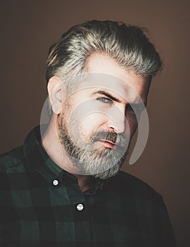 Serious man face. Close-up portrait of cheerful young man on gray background with copy space.