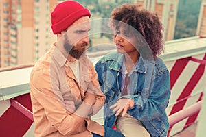 Serious man feeling offended and frowning while his girlfriend talking to him