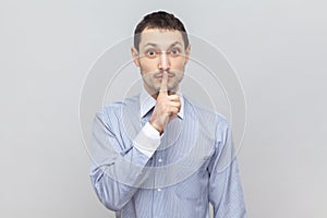 Serious man with finger near lips, showing shh gesture, asking to keep silence during lesson.