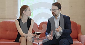 Serious man in formal suit talking to listening female colleague