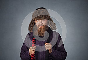 Serious man in fur hat dressed in a pullover holding red scarf posing