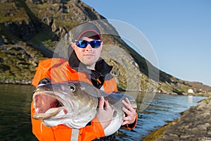 Serious man in glasses fisherman holding a fish ogromnyu Cod.