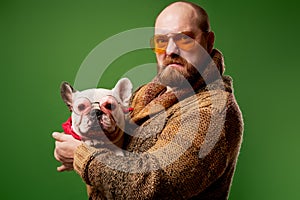 Serious man in glasses with french bulldog in his arms