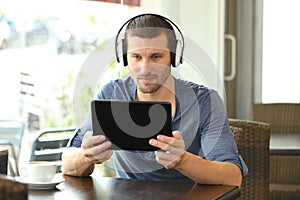 Serious man with headphones using a tablet in a bar