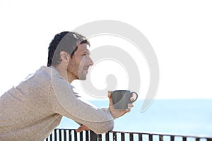 Serious man holding mug contemplating views from a balcony