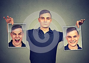 Serious man holding two different face emotion masks of himself