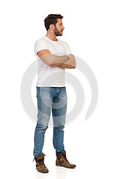 Serious Man In Jeans And White T-shirt Is Standing With Arms Crossed And Looking Away