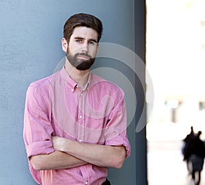 Serious man leaning on wall with arms crossed