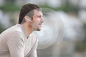 Serious man listening to music with wireless earphones