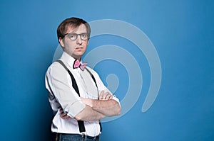 Serious man looking at camera with crossed arms on blue background with copy space