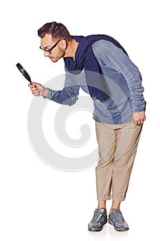 Serious man looking through magnifying glass