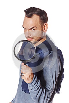 Serious man looking through magnifying glass