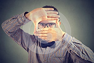 Serious young man making a frame with his hands looking at camera