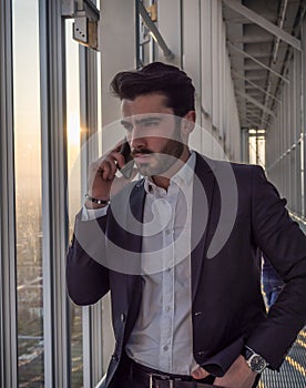 Serious man in modern building with cell phone