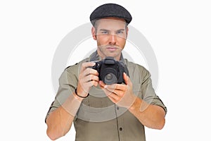 Serious man in peaked cap taking photo
