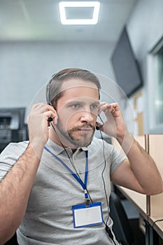 Serious man putting on headphones tuning headset