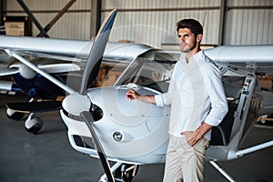 Serious man standing near small airplane