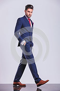 Serious man in suit walking with hands in pockets