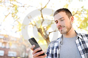 Serious man uses a smart phone walking in a park