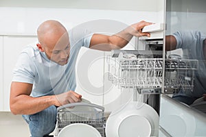 Serious man using dish washer in kitchen