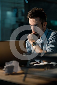 Serious man using laptop at work