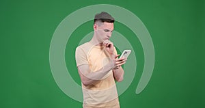 Serious man using phone on green background